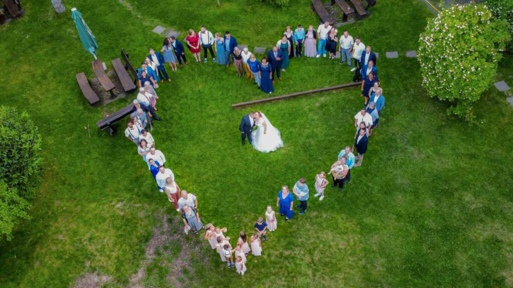 Herz aus Menschen von oben fotografiert. In der Mitte das Brautpaar